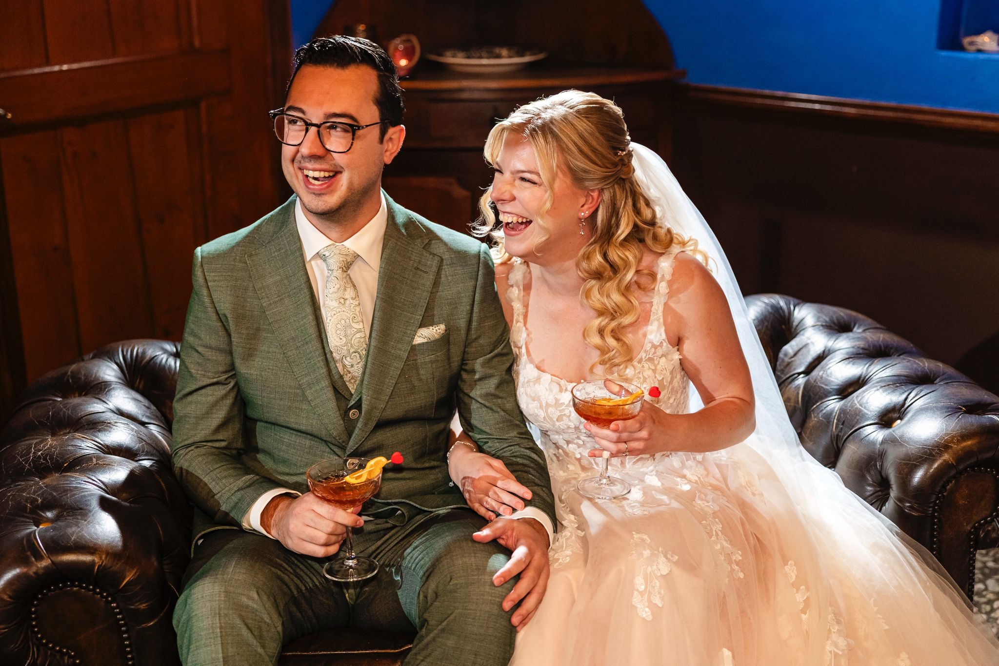 Echtpaar lacht samen op de bank met een cocktail