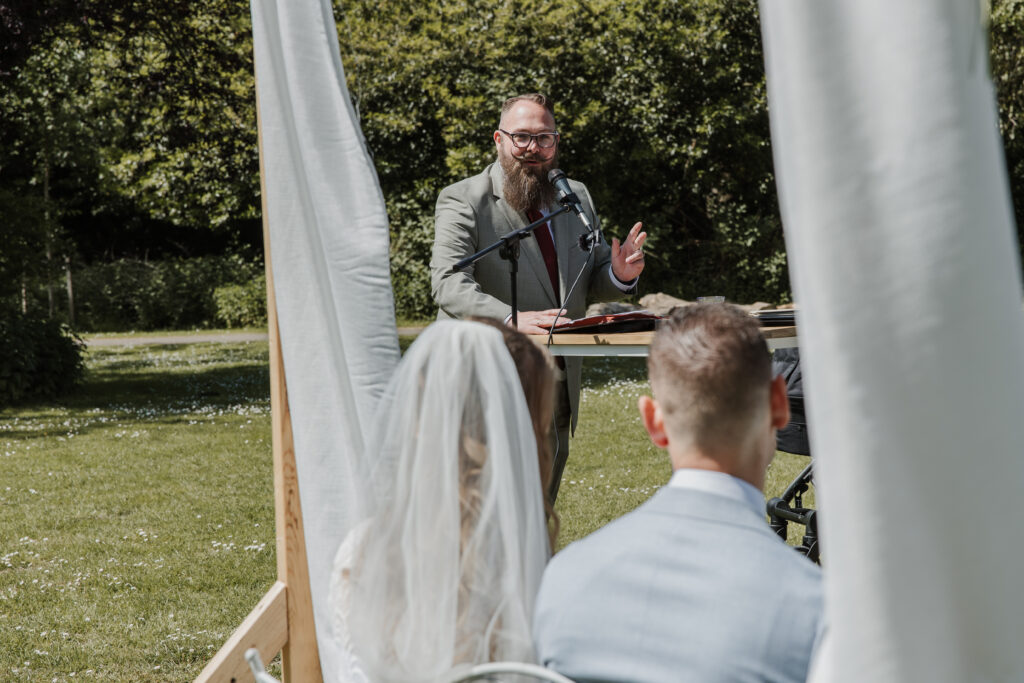 Jorg spreekt het bruidspaar toe tijdens een buitenceremonie