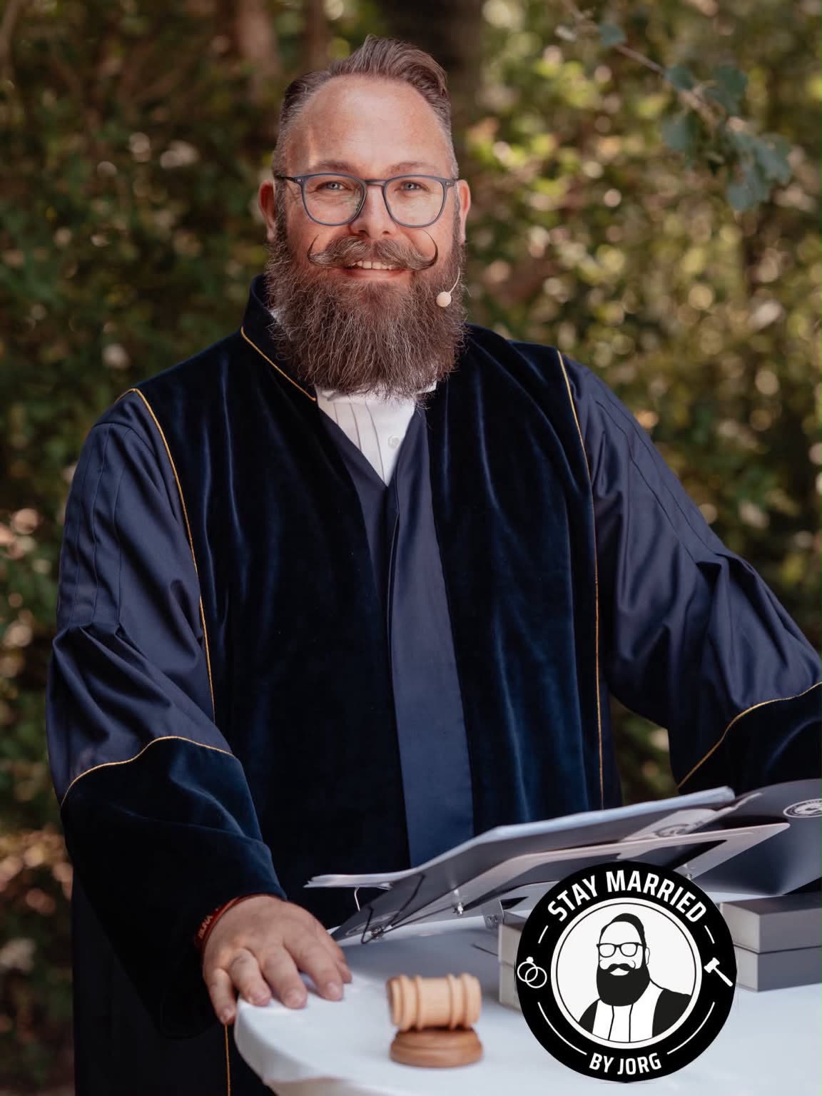 Portret van trouwambtenaar Jorg in toga met het Stay Married-logo